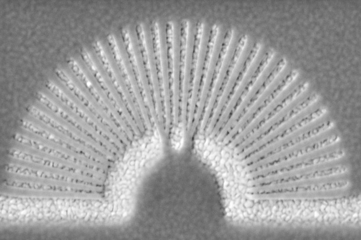 The image (above) shows a metamaterial hyperlens. The light-colored slivers are gold and the darker ones are PMMA (a transparent thermoplastic). Light passes through the hyperlens improving the resolution of very small objects. (Img: University of Buffalo)